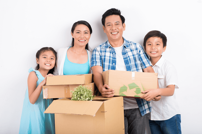 Family of 4 smiling holding moving boxes